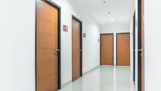 A hallway with wooden doors and a white tiled floor.