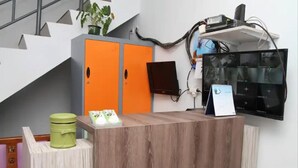 A reception desk with a wooden finish, a green trash bin, and an orange cabinet.