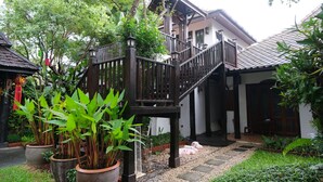 A traditional house with a wooden staircase, potted plants, and a stone pathway. - Vimarn Kaew Village and Resort (Chiang Mai)