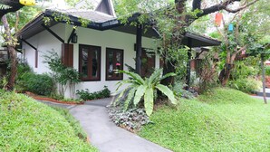 A traditional house with a sloped roof, surrounded by lush greenery and a pathway leading to the entrance. - Vimarn Kaew Village and Resort (Chiang Mai)