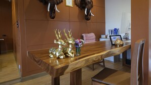 A dining area with a wooden table, two mounted elephant heads on the wall, and decorative reindeer figures. - Vimarn Kaew Village and Resort (Chiang Mai)