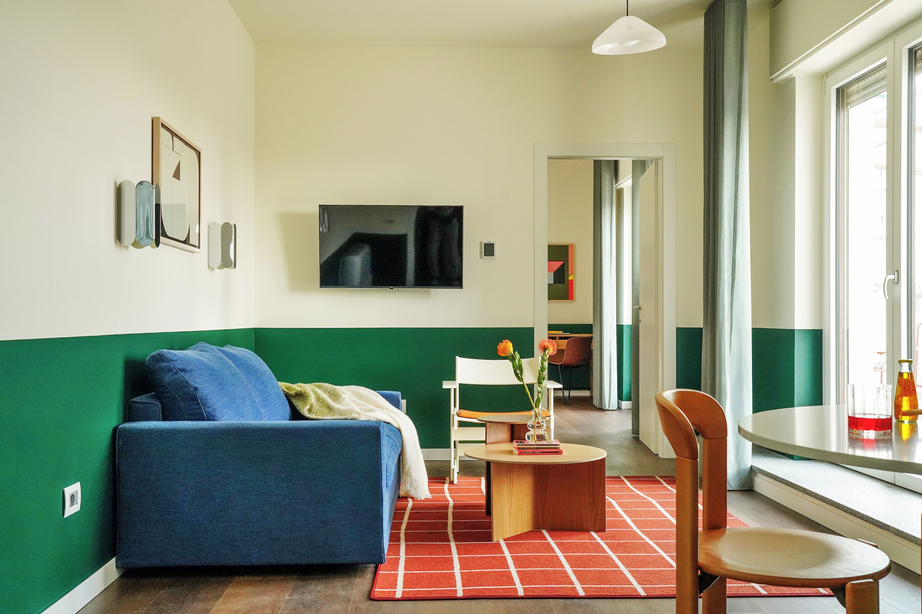 Un salon moderne avec un canapé bleu, une table basse en bois et un tapis à carreaux rouges et blancs.