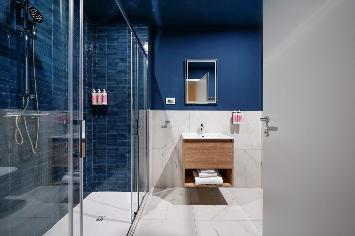 A modern bathroom with a glass shower enclosure, a wooden vanity, and a mirror above the sink.