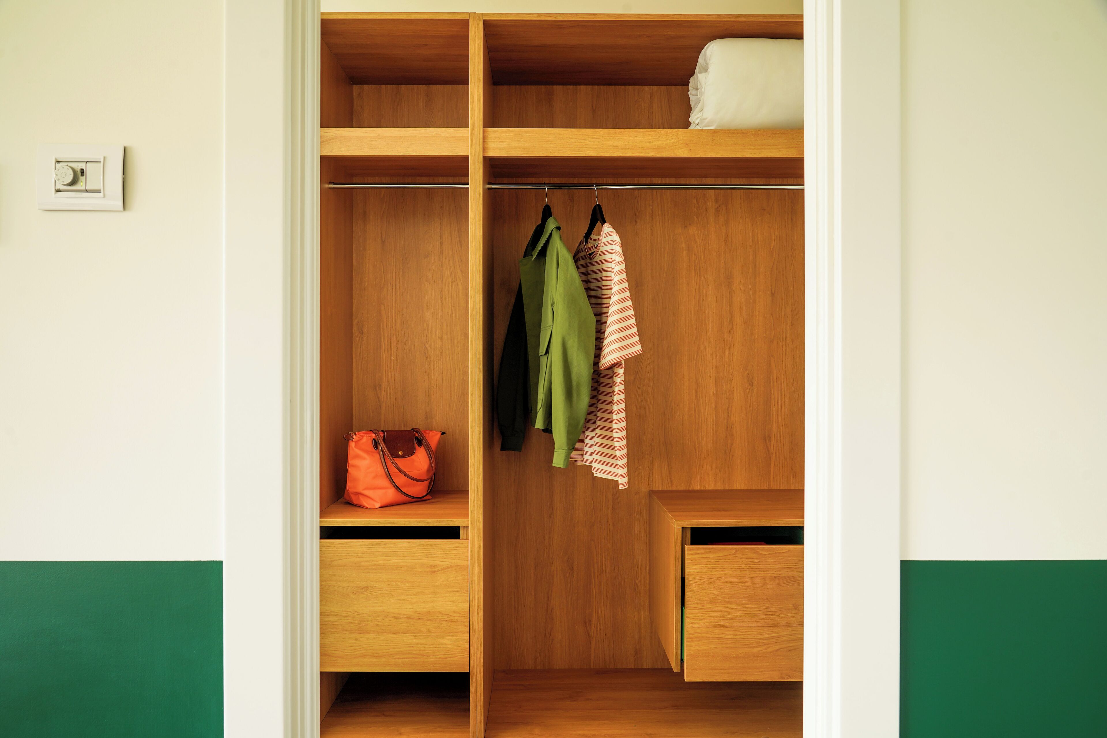 A wooden wardrobe with shelves, a hanging rod, and a bench.