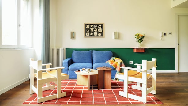Un salon avec un canapé bleu, une table basse en bois et deux chaises blanches.
