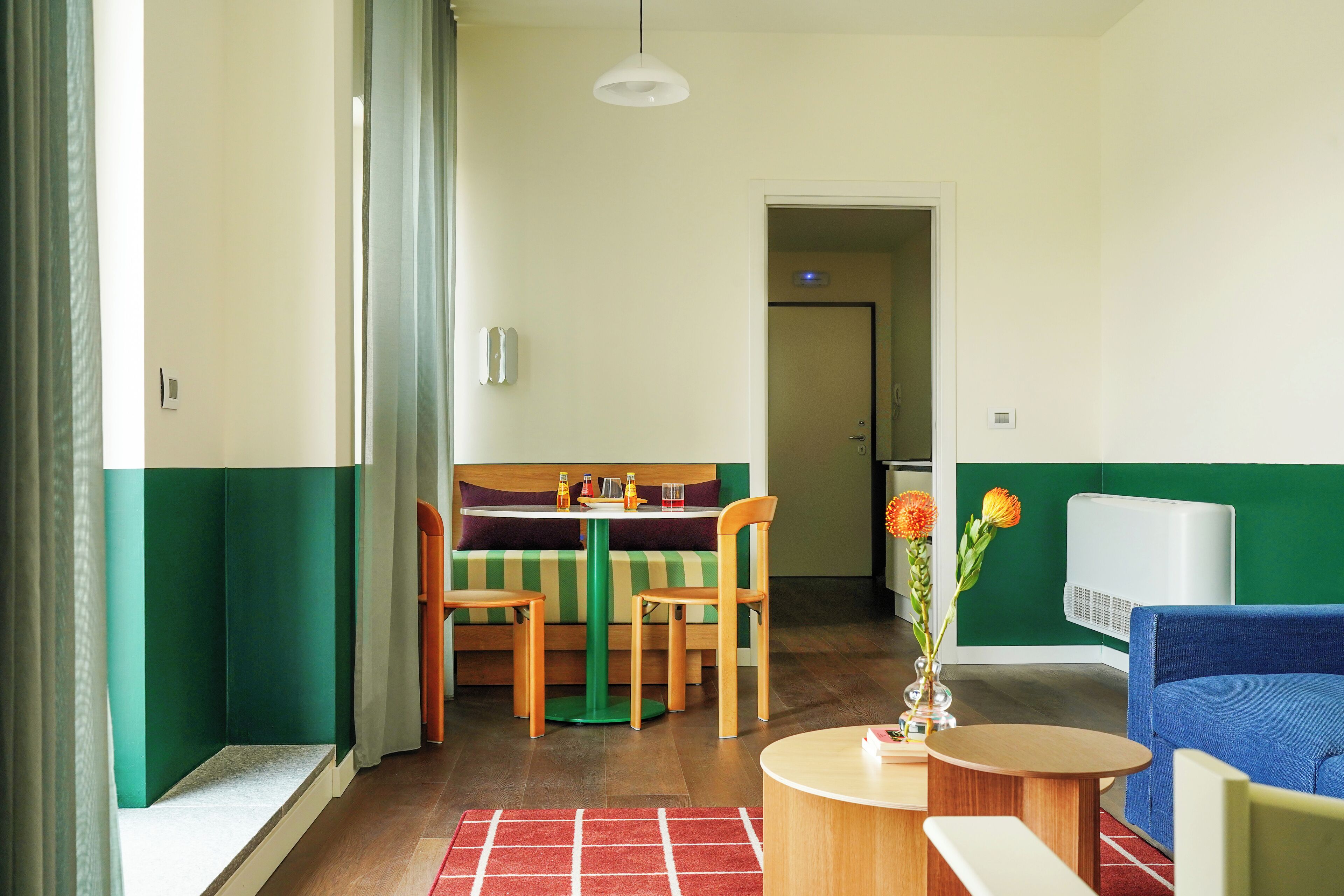 Ein Zimmer mit Esstisch, Stühlen, einer Couch und einem kleinen Tisch mit einer Vase.