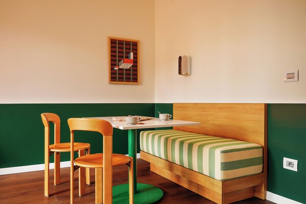 A small room with a wooden bed, a green wall, and a table with chairs.