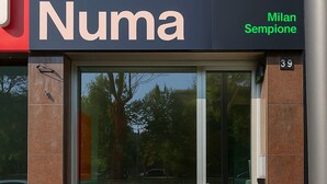 Une devanture avec une grande vitrine, le nom « Numa » affiché en grand au-dessus, et « Milan Sempione » en caractères verts sur la droite.