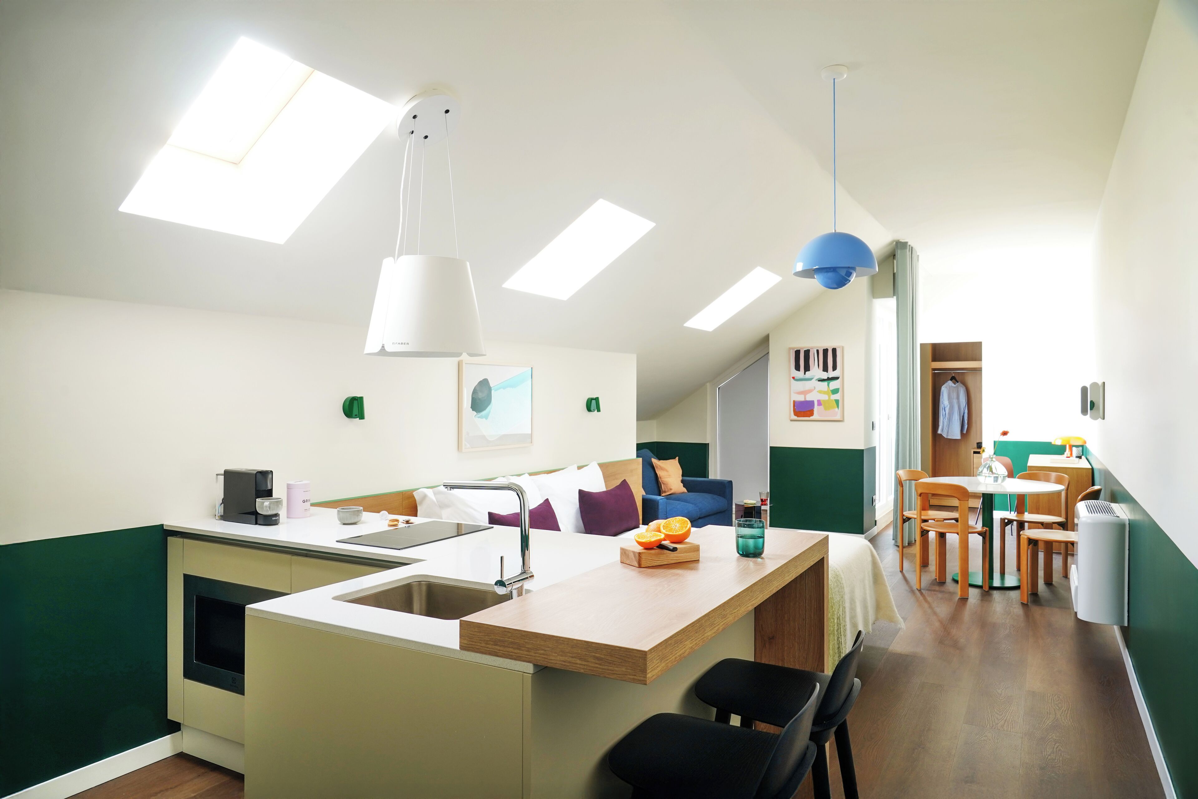 Una cocina moderna con una isla central, un área de comedor con sillas de madera y un armario visible al fondo.