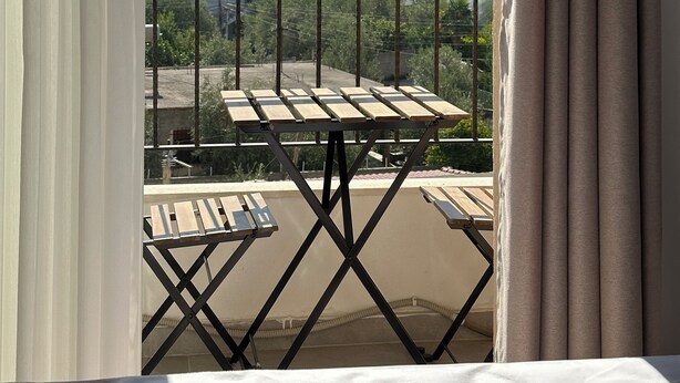 A balcony with a table and chairs, overlooking a hillside with buildings. - Cobalt Apartments. 1-bedroom apartment in Vlora. (Vlora)