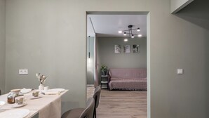 A dining area with a table set for four, a sofa in the background, and a ceiling light fixture.