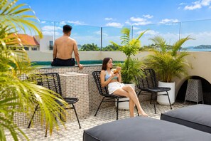 Une terrasse sur le toit avec une piscine, des chaises longues et des plantes en pot.