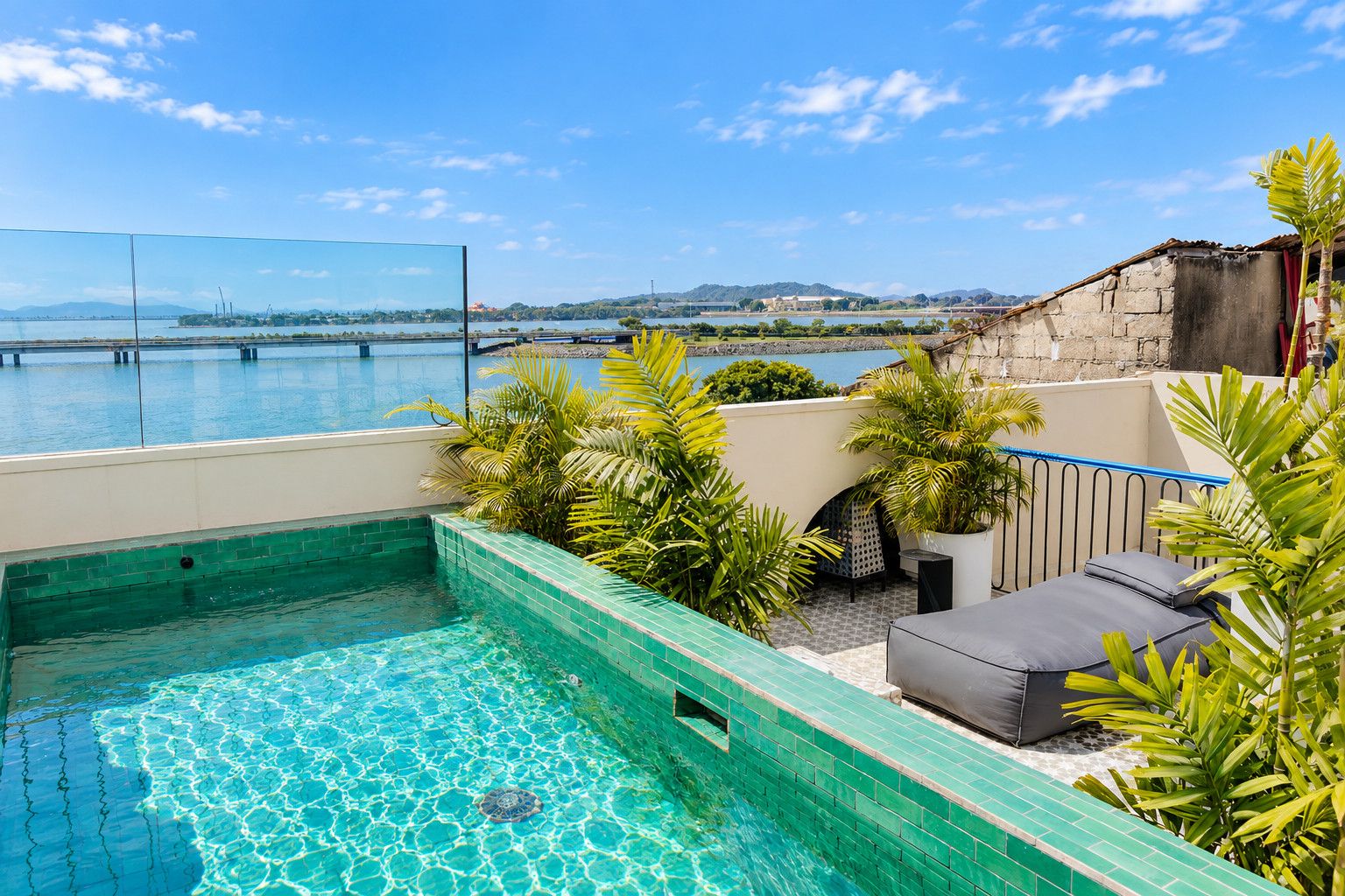 A rooftop swimming pool with a view of a body of water and distant hills.