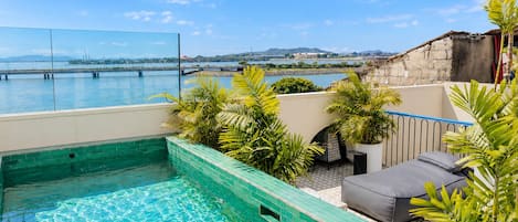 Una piscina en la azotea con vistas al agua y colinas distantes.