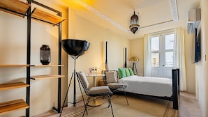 A hotel room with a bed, a desk, a chair, a lamp, and a shelf. - Balcony Superior with communal pool Ma8 (Ciudad de Panamá)