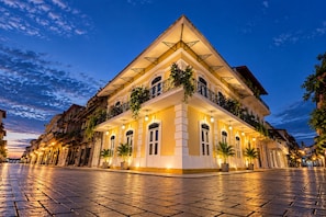 Un hotel dallo stile architettonico classico, con un cortile centrale, numerosi balconi con piante e un'atmosfera accogliente e invitante.