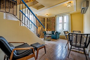 Un salon avec un escalier, un canapé, une table à manger et une chaise.