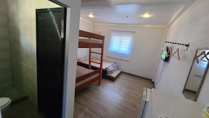 A compact room with a bunk bed, a small window with blinds, a radiator, and a wall-mounted TV. - Camp Rofelio Surfing Beach Resort (San Felipe)