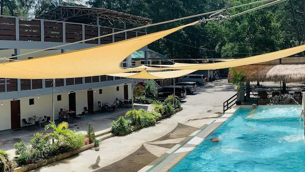 A swimming pool with a clear blue water, surrounded by a deck area with outdoor seating and a building in the background. - Camp Rofelio Surfing Beach Resort (San Felipe)
