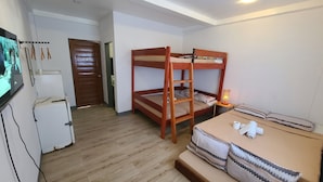 A room with bunk beds, a small table with a lamp, a refrigerator, and a TV. - Camp Rofelio Surfing Beach Resort (San Felipe)