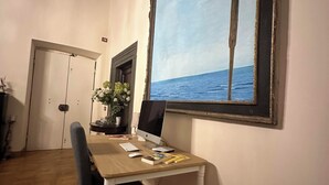 A dining area with a wooden table, a computer, and a large painting of a seascape. - In Center Lucca Lovely Home (Lucca)