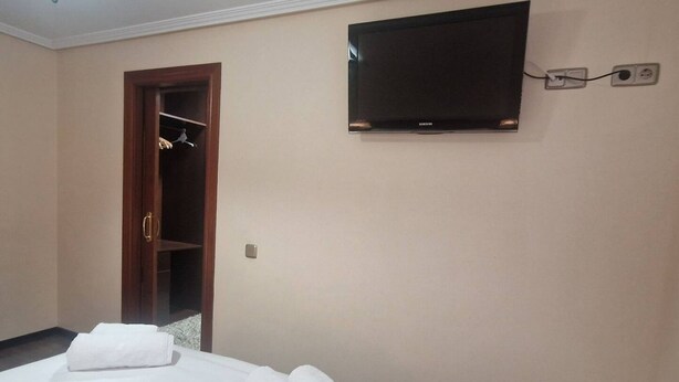 Une chambre d’hôtel avec un lit, un téléviseur fixé au mur et une armoire en bois.