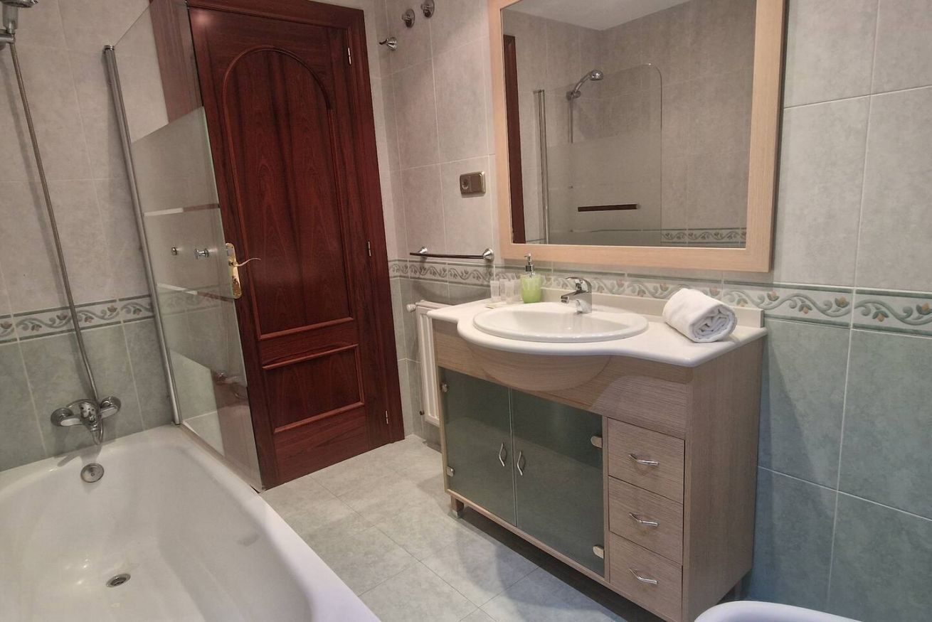 Een badkamer met een bad, een wastafel met spiegel en een douche.