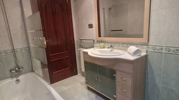 Een badkamer met een bad, een wastafel met spiegel en een douche.
