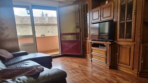 Un salon avec un canapé en cuir, un téléviseur à écran plat, des meubles en bois et une porte-fenêtre coulissante donnant sur un espace extérieur.