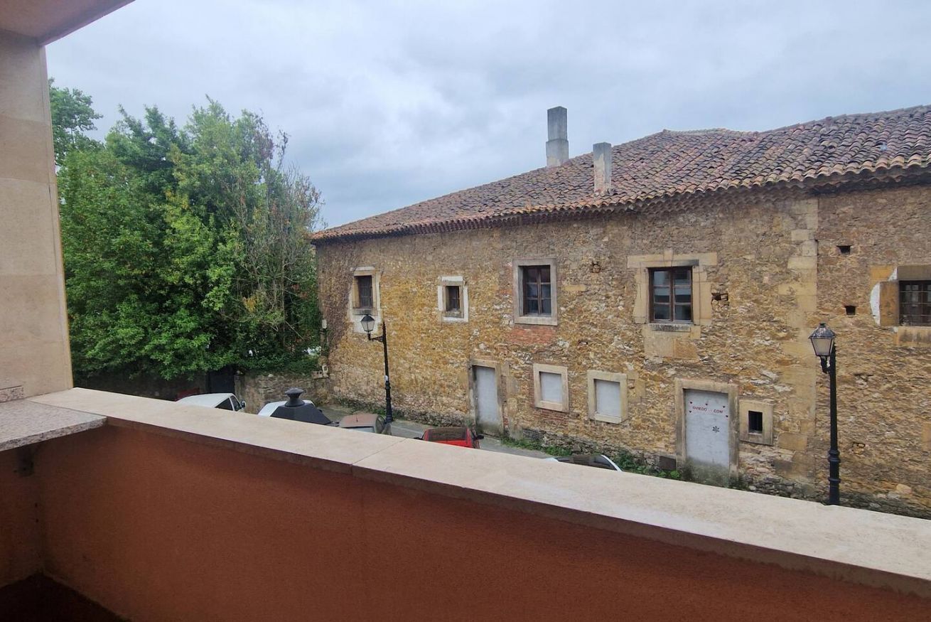 Un edificio de piedra con tejado de tejas, varias ventanas y un balcón con vistas a un patio.