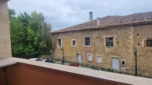 Un bâtiment en pierre avec un toit en tuiles, plusieurs fenêtres et un balcon donnant sur une cour.