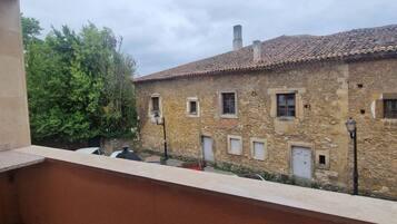 Un edificio de piedra con tejado de tejas, varias ventanas y un balcón con vistas a un patio.