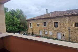 Un edificio de piedra con tejado de tejas, varias ventanas y un balcón con vistas a un patio.