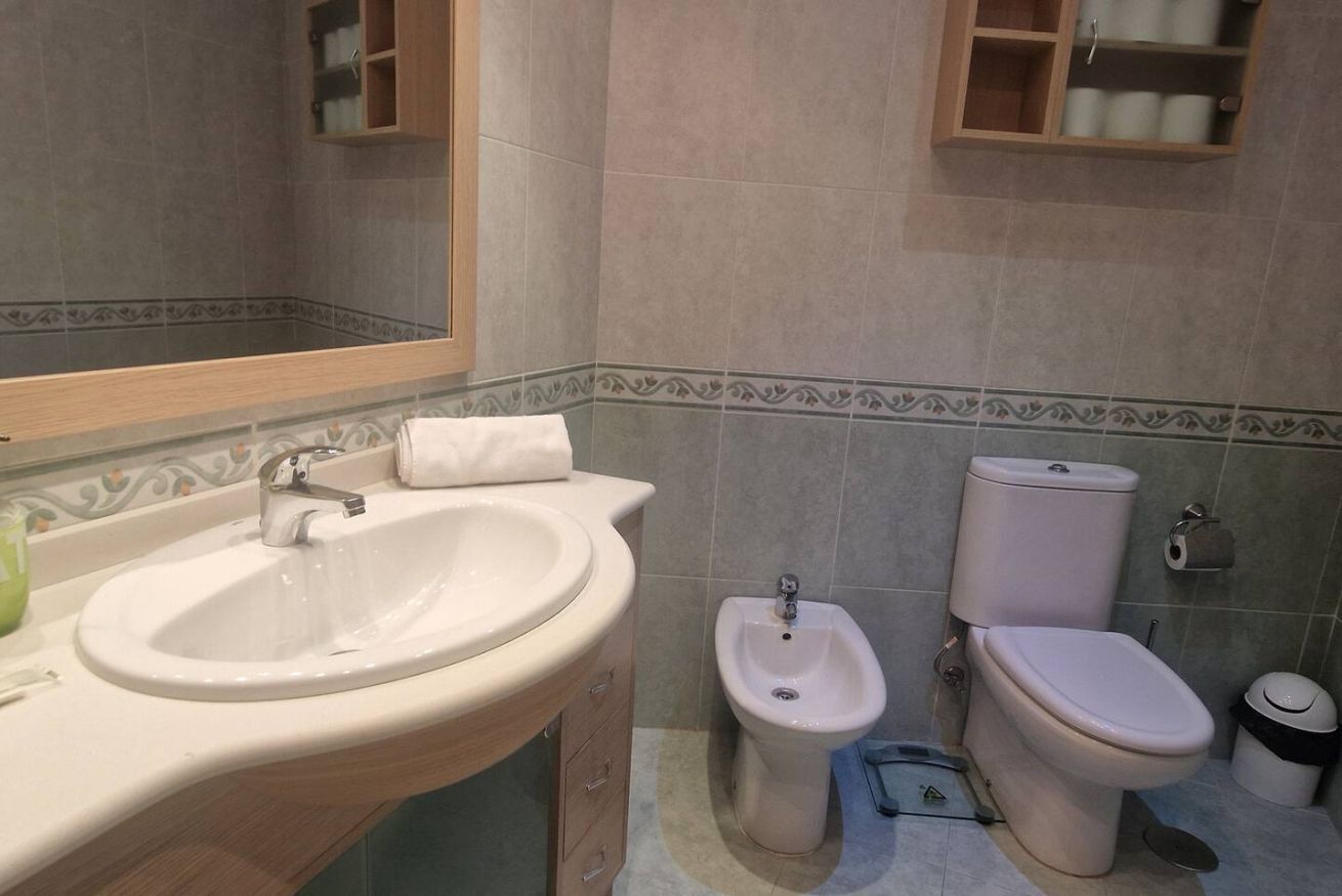 Een badkamer met een wastafel, bidet, toilet en spiegel.