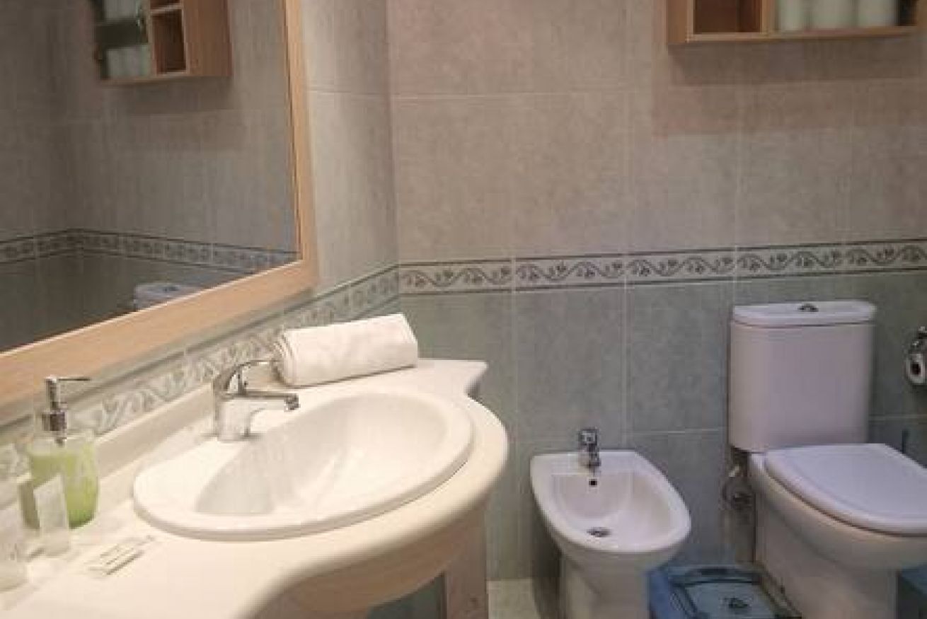 Een badkamer met een wastafel, bidet, toilet en een spiegel.
