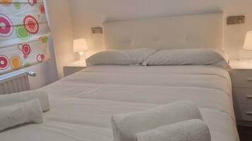 Una habitación de hotel con una cama, dos mesitas de noche, una pared con un diseño circular colorido y una ventana.