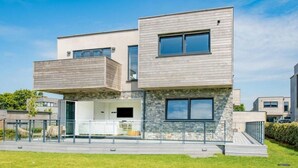 Ein modernes, zweistöckiges Haus mit Flachdach, großen Fenstern und einer Steinaußenwand.