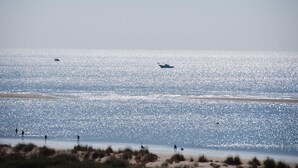 Ein Strand mit einem Boot im Wasser und Menschen am Ufer.
