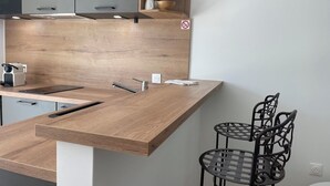 Una cocina moderna con encimera de madera, un lavamanos empotrado y una silla de metal.