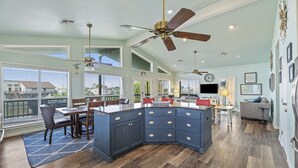 A spacious kitchen with a central island, large windows, and ceiling fans.
