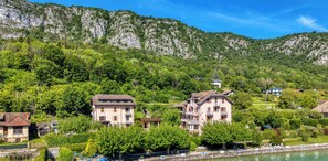 A hillside village with traditional buildings, a river, and a mountain backdrop.