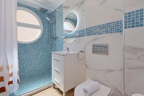 Bathroom features a shower, vanity with sink and mirror, and a toilet and bidet.