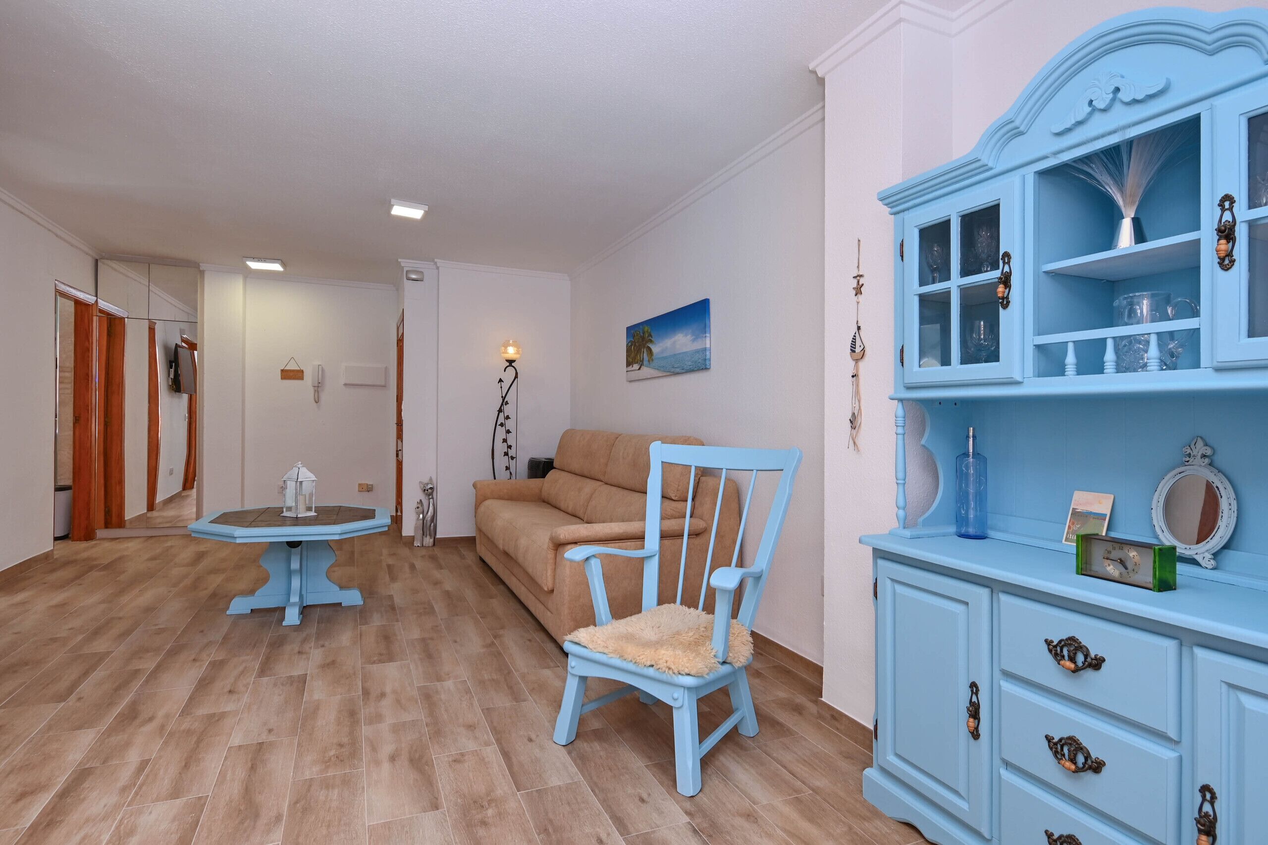 A room with a blue cabinet, a chair, a table, and a sofa.