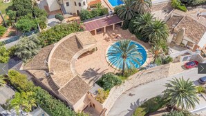 Vue aérienne d’un complexe hôtelier doté d’une piscine circulaire, de palmiers et d’un patio couvert.