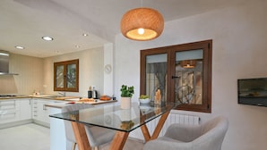 Une cuisine moderne avec une table à manger en verre, des chaises en bois et un luminaire suspendu.