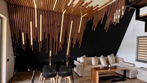 A modern living room with a unique wooden ceiling design, a sofa, a coffee table, and black chairs. - Lost In Sky (Yenokavan)