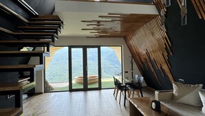A modern interior with a wooden staircase, a glass dining area, and a view of a mountainous landscape. - Lost In Sky (Yenokavan)