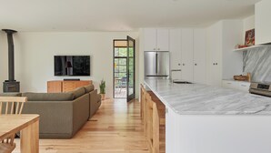 Una cocina moderna con armarios blancos, encimera de mármol y estufa integrada.