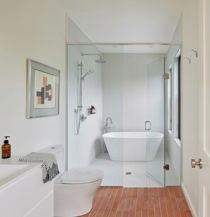A modern bathroom with a glass-enclosed shower, a freestanding bathtub, and a white toilet.
