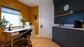 A modern kitchen with a wooden desk, a black office chair, a microwave, and a coffee maker. - Modern Studio in Angel | Walk to Tube | Near Regent’s Canal (London)